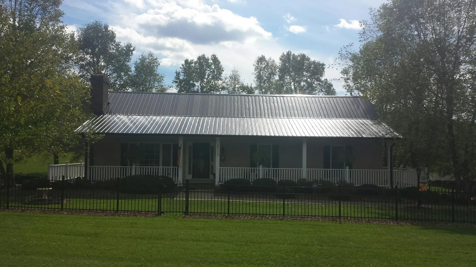 Gray metal roof on a brick ranch with a full width front porch — Gutter Guard Installation work by our crew in Dallas