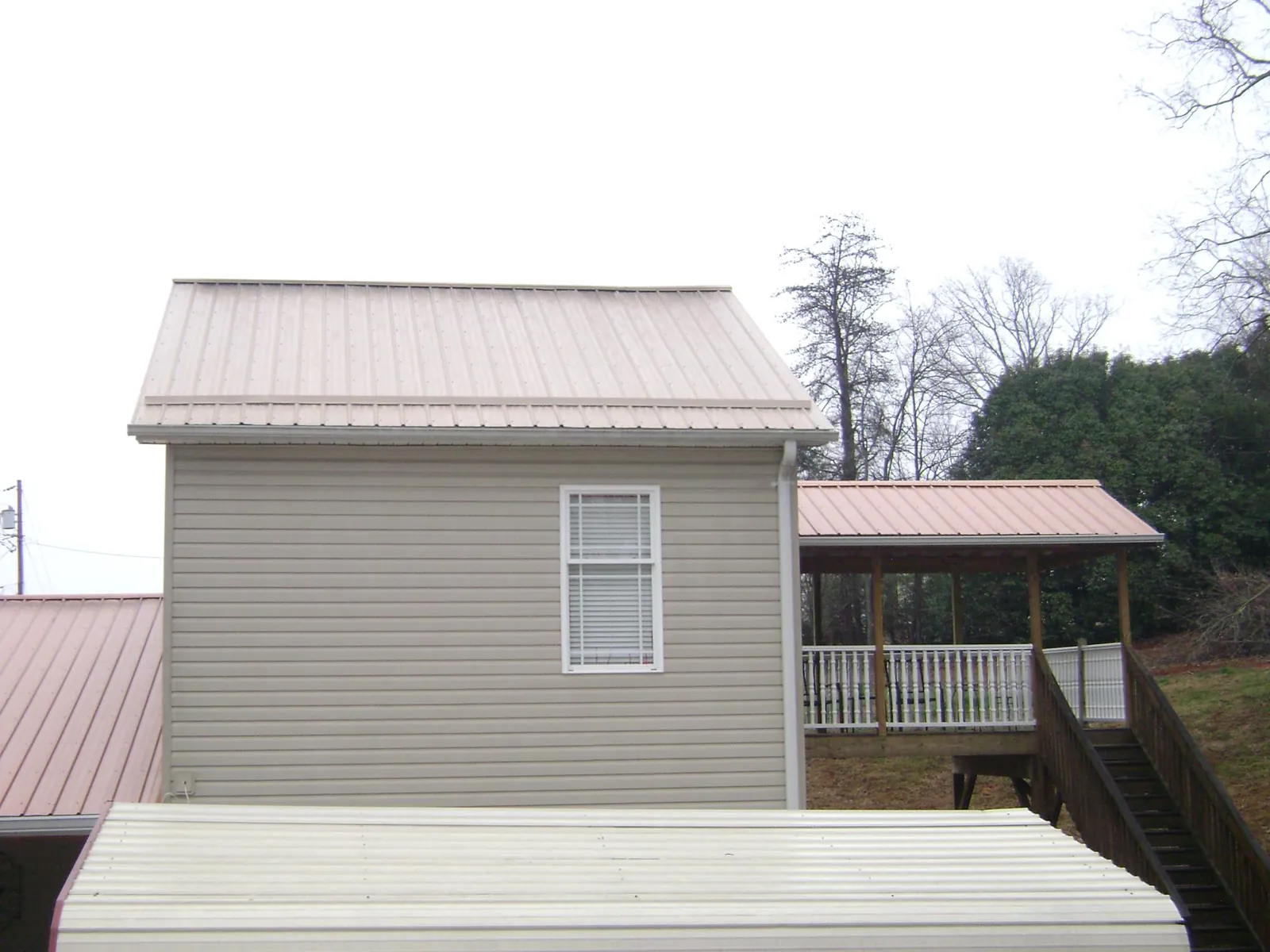 Tan metal roofs on a two story addition and attached porch, from a Roof Replacement job in Dallas